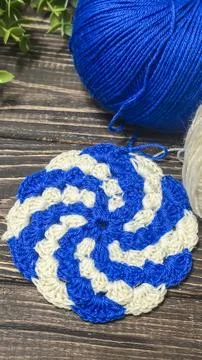 A raised openwork pattern knitted with colored yarn on a wooden background. Foto stock