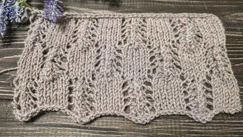 A raised openwork pattern knitted with colored yarn on a wooden background. Foto stock