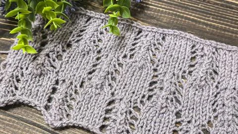 A raised openwork pattern knitted with colored yarn on a wooden background. Stock Photos