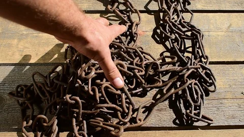 Raises a rusty chain from a wooden floor Stock Footage 117478144