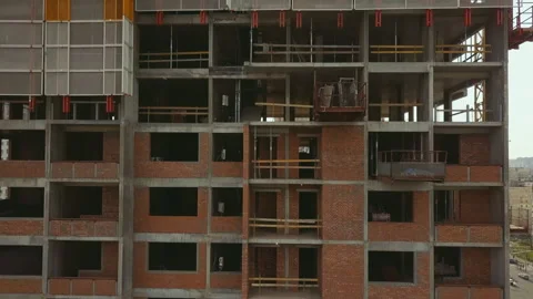 Raising the camera up along a building under construction with empty floor spans Stock Footage 152817695