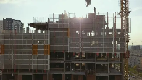 Raising the camera up along a building under construction with empty floor spans Stock Footage 157474064