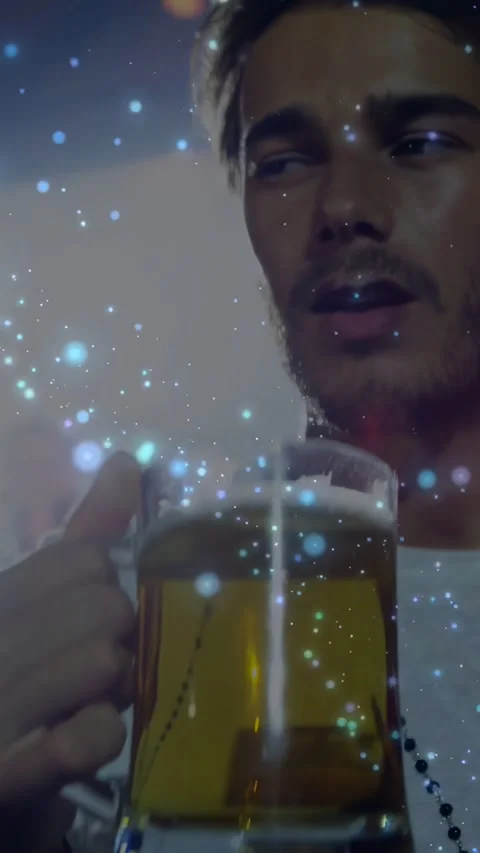 Raising man wearing white tee with beads, drinking beer from stein at bar, Stock Footage 334317213