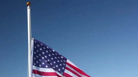 Raising the USA Flag - flying in the wind outside with Blue sky - American Stock Footage 131843045