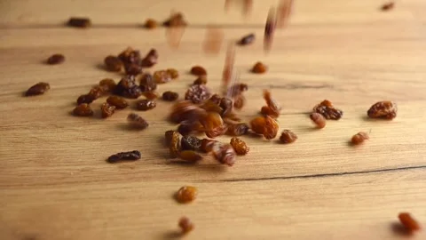 Raisins are falling on a wooden table. Slow motion video Stock Footage 152952832