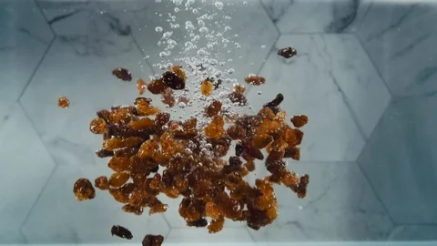 Raisins dropping into water Stock Footage 129609223
