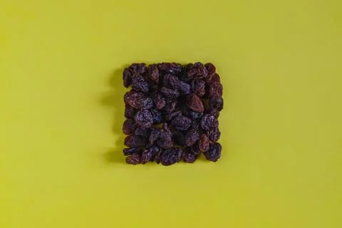 Raisins in the shape of a square on a yellow background (without shape). Stock Photos