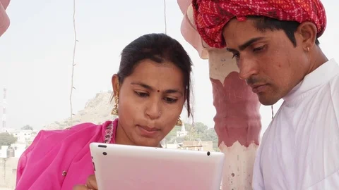 Rajasthani couple working learning teaching sharing on a tablet wearing pink sar Stock Footage 70340299