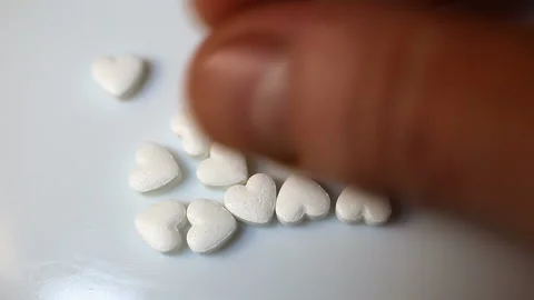 Rake in a handful and touch small white pills in the form of a heart. Contains p Stock Footage 145374509