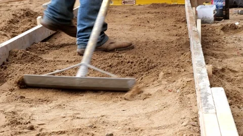 A rake tool is used to level dirt in preparation for a new sidewalk. Stock Footage 154665924