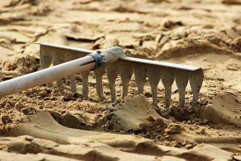 Rake tools lie on the sand, prepared for laying paving slabs. Photos