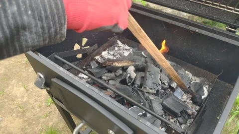Raking coal with a stick in the grill - in the frame of the hand Stock Footage 155630869