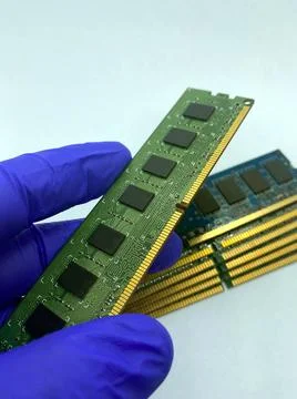 RAM chip kept on gloved hand against a stack of RAM chips closeup isolated on Stock Photos