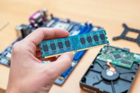 RAM memory module in hand. Motherboard and hard disk in background. Concept o 스톡 사진