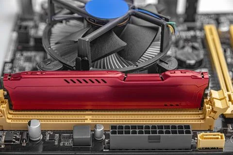 A RAM module installed on a computer motherboard next to a CPU cooling fan. Stock Photos