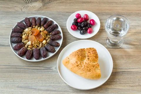 Ramadan bread, decorated with dried dates,olives and a glass of water Stock Photos