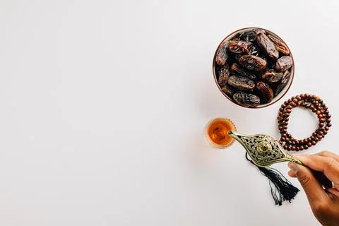 Ramadan flat lay with tea, dates, and prayer beads on a white background. Stock Photos