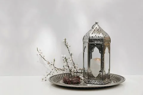 Ramadan Kareem table setting. Date fruit, white flowers and burning silver Fotos Stock