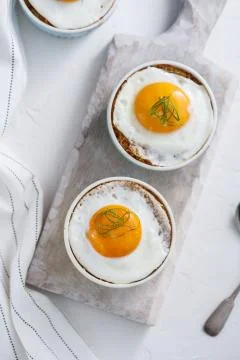 Ramekins baked eggs on white background, top view Stock Photos
