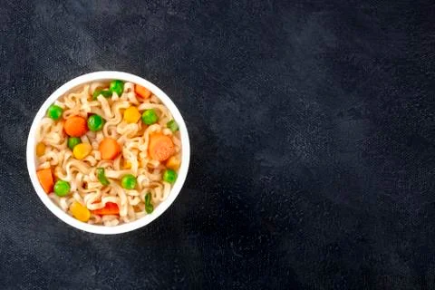 Ramen cup, instant soba noodles in a plastic cup, with green peas and carrot Stock Photos