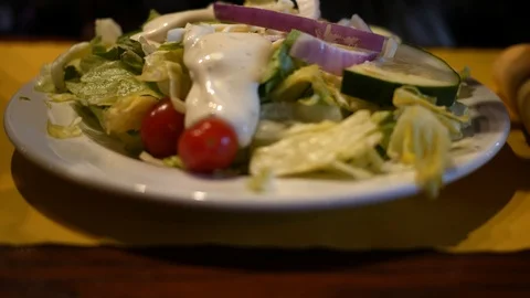 Ranch dressing being poured over a Caesar salad in a restaurant Stock Footage 88065653