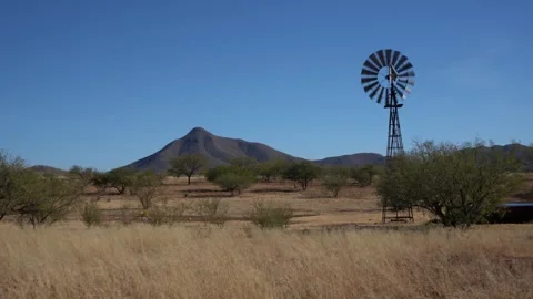 A ranch windmill on a high desert prairie and scenic mountains Stock Footage 295904924