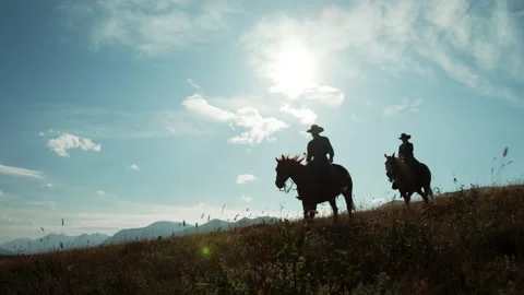 Ranchers riding horses near mountain top towards camera Stock Footage