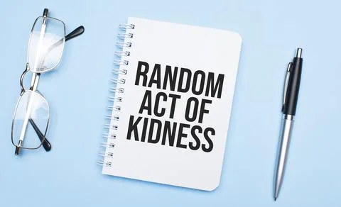 Random act of kidness words in white notepad, pen and glasses on blue backgro Stock Photos