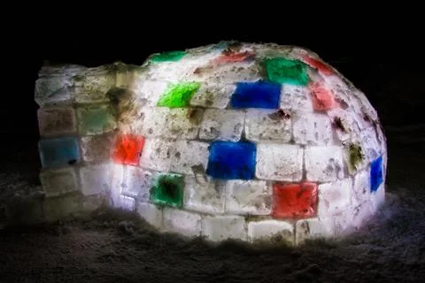 Random color igloo, illuminated from the inside on a dark background. Stock Photos
