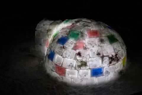 Random color igloo, illuminated from the inside on a dark background. Stock Photos