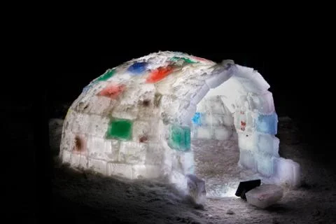Random color igloo, illuminated from the inside on a dark background. Stock Photos