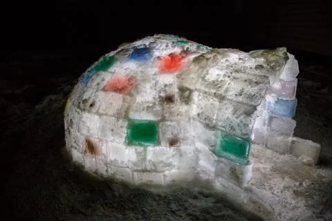 Random color igloo, illuminated from the inside on a dark background. Stock Photos