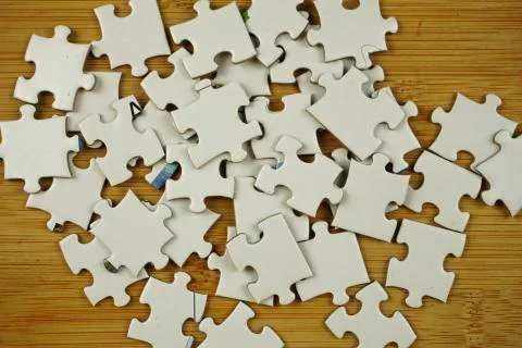 Random jigsaw puzzle incomplete concept on wooden background. Copy space for Stock Photos