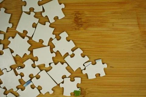 Random jigsaw puzzle incomplete concept on wooden background. Copy space for Stock Photos