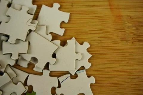 Random jigsaw puzzle incomplete concept on wooden background. Copy space for Stock Photos