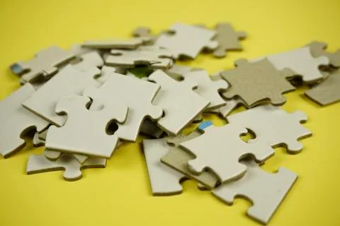 Random jigsaw puzzle incomplete concept on yellow background Stock Photos