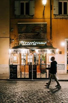 Random man in a face mask walking next to pizzeria in Rome, Italy Stock Photos