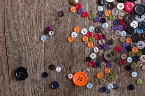 Random Scattering of small multicolored buttons on a wooden floor boards Foto stock