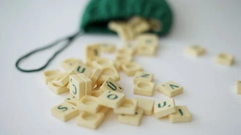 Random Scrabble game letter tiles with score value coming out of their green dra Stock Footage 126976019