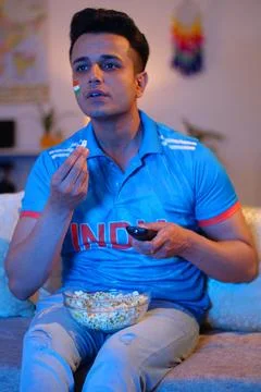 Random shot of a man having popcorn while watching a cricket match on televis... Foto stock