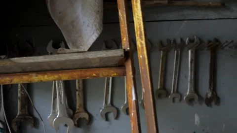 Random tools and wrenches hanging on old, dark garage wall Stock Footage 195999472