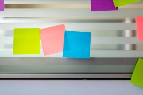 Randomly scattered colored sticky notes over glass screen of a bench desk Stock Photos