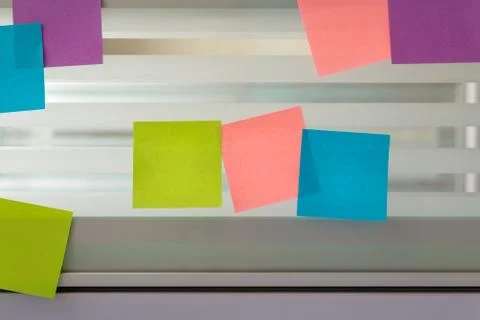 Randomly scattered colored sticky notes over glass screen of a bench desk Stock Photos