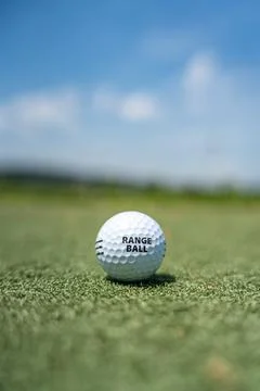 Range ball sitting on driving range tee under blue sky Stock Photos