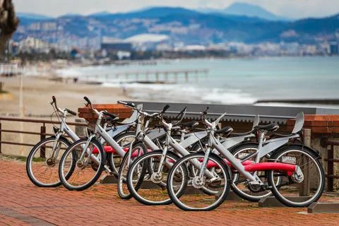 A range of different bicycles for rent parked against the backdrop of the bea Stock Photos