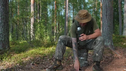 The ranger, during training in the forest, opens his thermos to have some tea Stockbeeldmateriaal 315361689