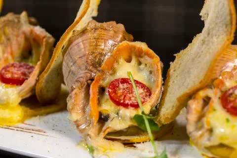 Rape baked with cheese, cherry tomato. Shellfish baked in shell. Rapane. Stock Photos