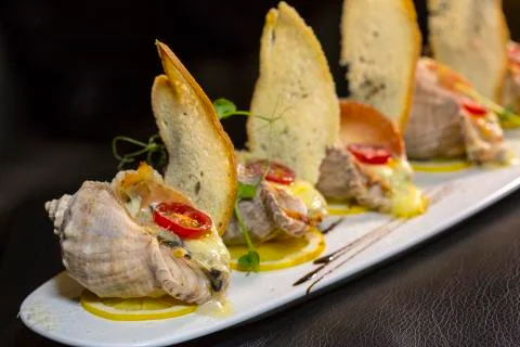 Rape baked with cheese, cherry tomato. Shellfish baked in shell. Rapane. Stock Photos