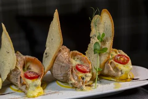 Rape baked with cheese, cherry tomato. Shellfish baked in shell. Rapane. Stock Photos
