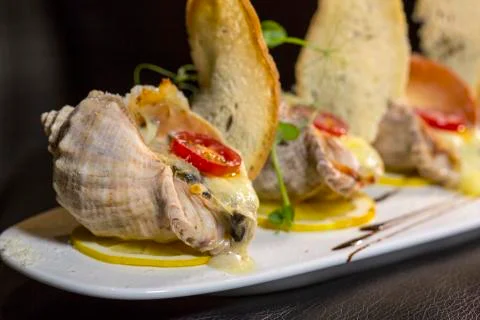 Rape baked with cheese, cherry tomato. Shellfish baked in shell. Rapane. Stock Photos